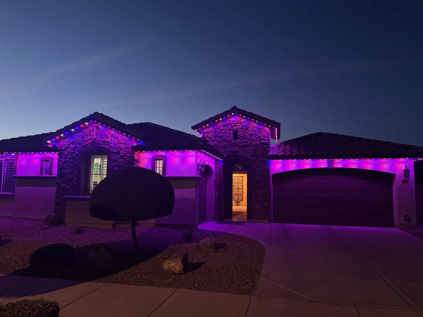 The same stone front home lit in purple using the same permanent LED lighting