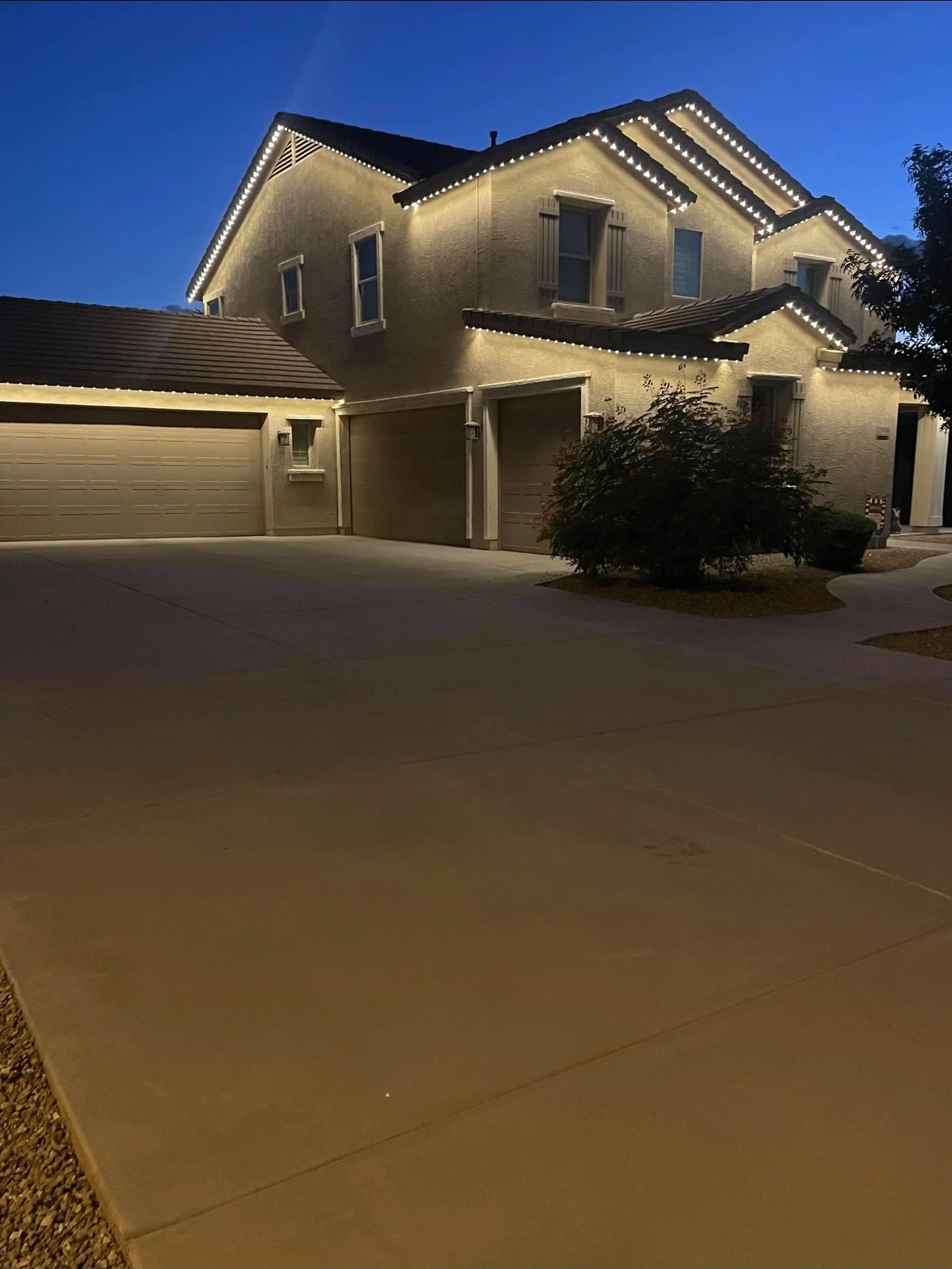 Two story home at dusk with warm white permanent lighting