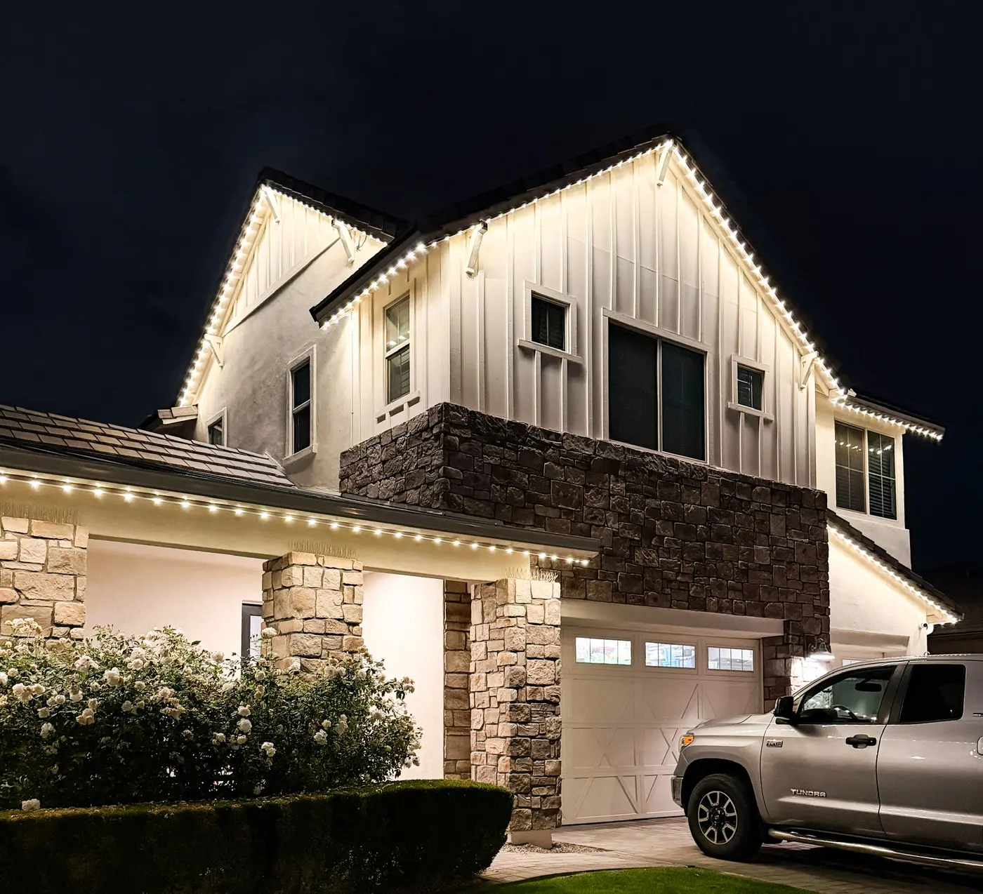Modern farmhouse with warm white permanent lighting on every roofline