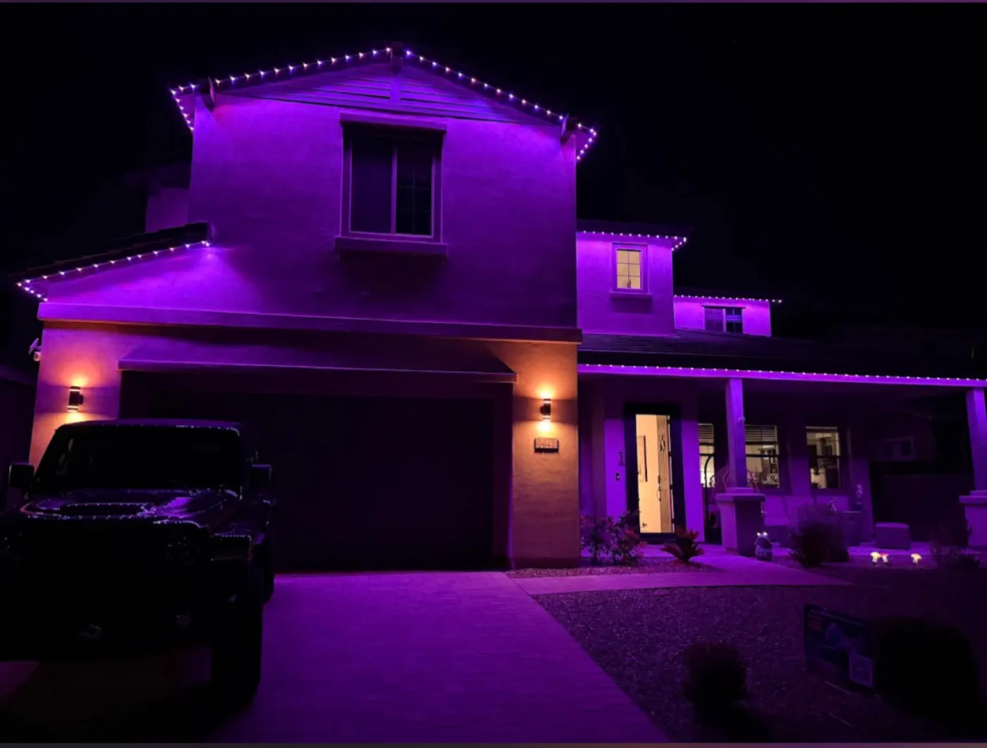 Two story stucco home washed in violet permanent LED lighting